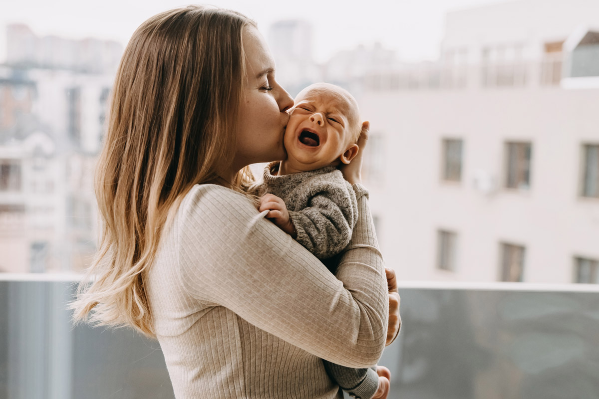 Mamma che tiene in braccio il suo bimbo che piange - il sonno e il pianto dei neonati