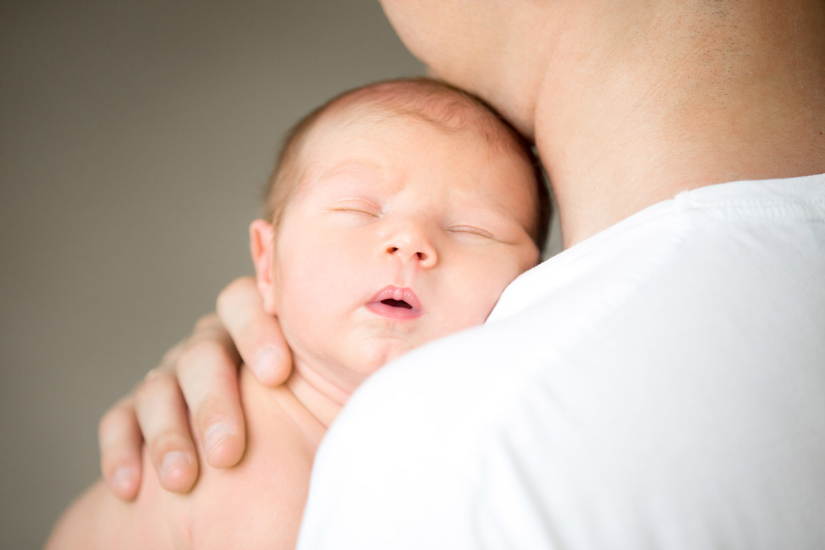 Neonato che dorme sulla spalla del papà - l'importanza del contatto