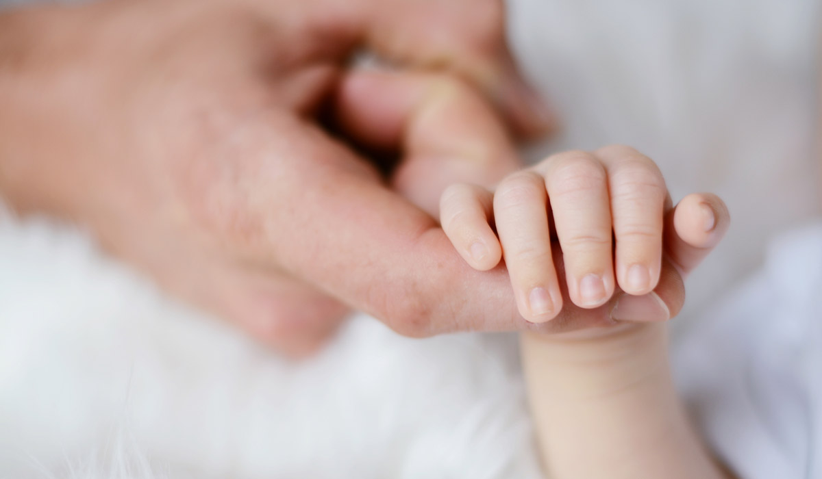 Neonato che afferra la mano del genitore - Mamma e papà insieme per accogliere il neonato