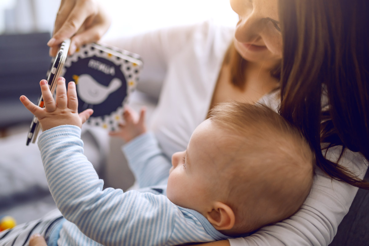 Bimbo che osserva un libro con la mamma - le prime parole e lo sviluppo del linguaggio