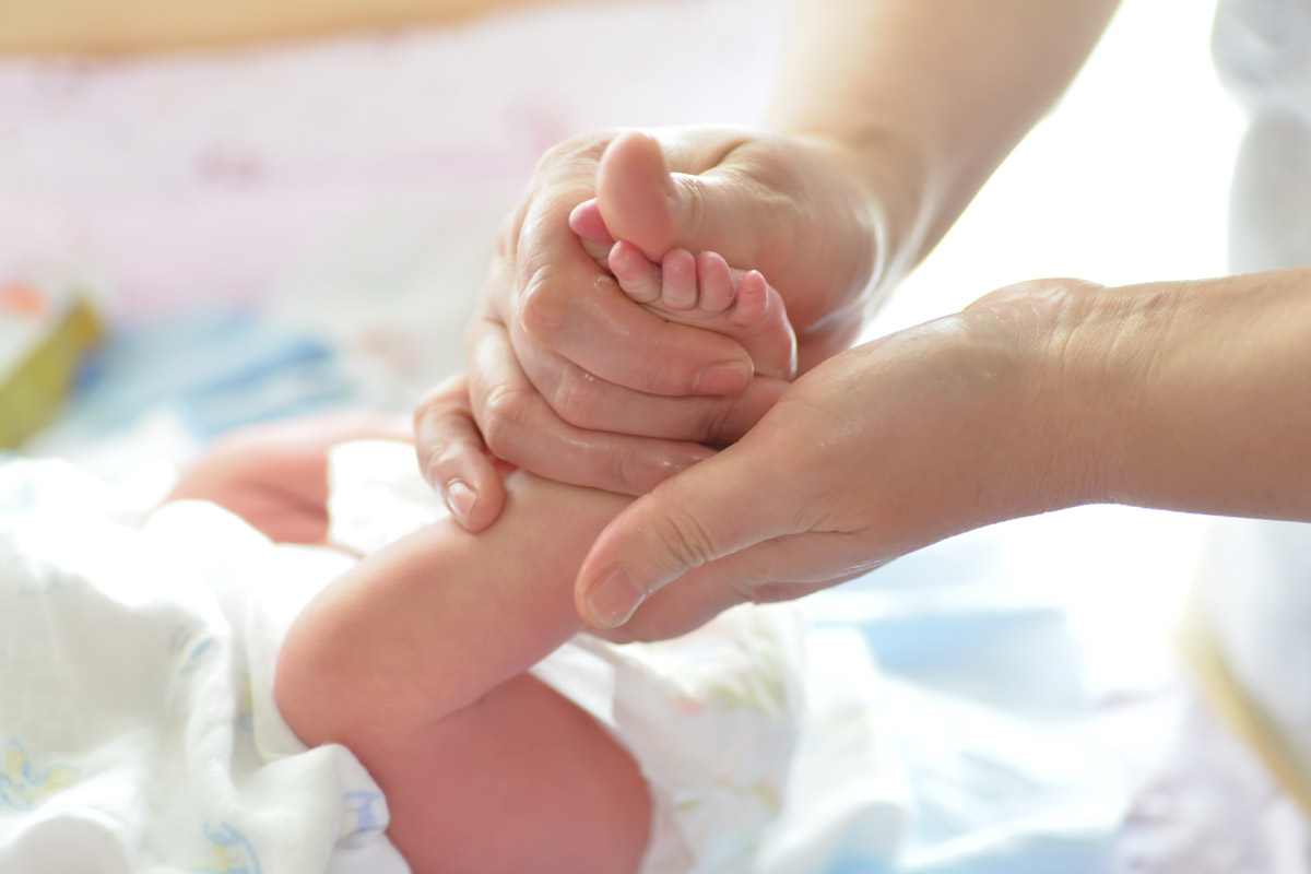 Mamma che massaggia i piedini del suo bambino - Bonding neonatale