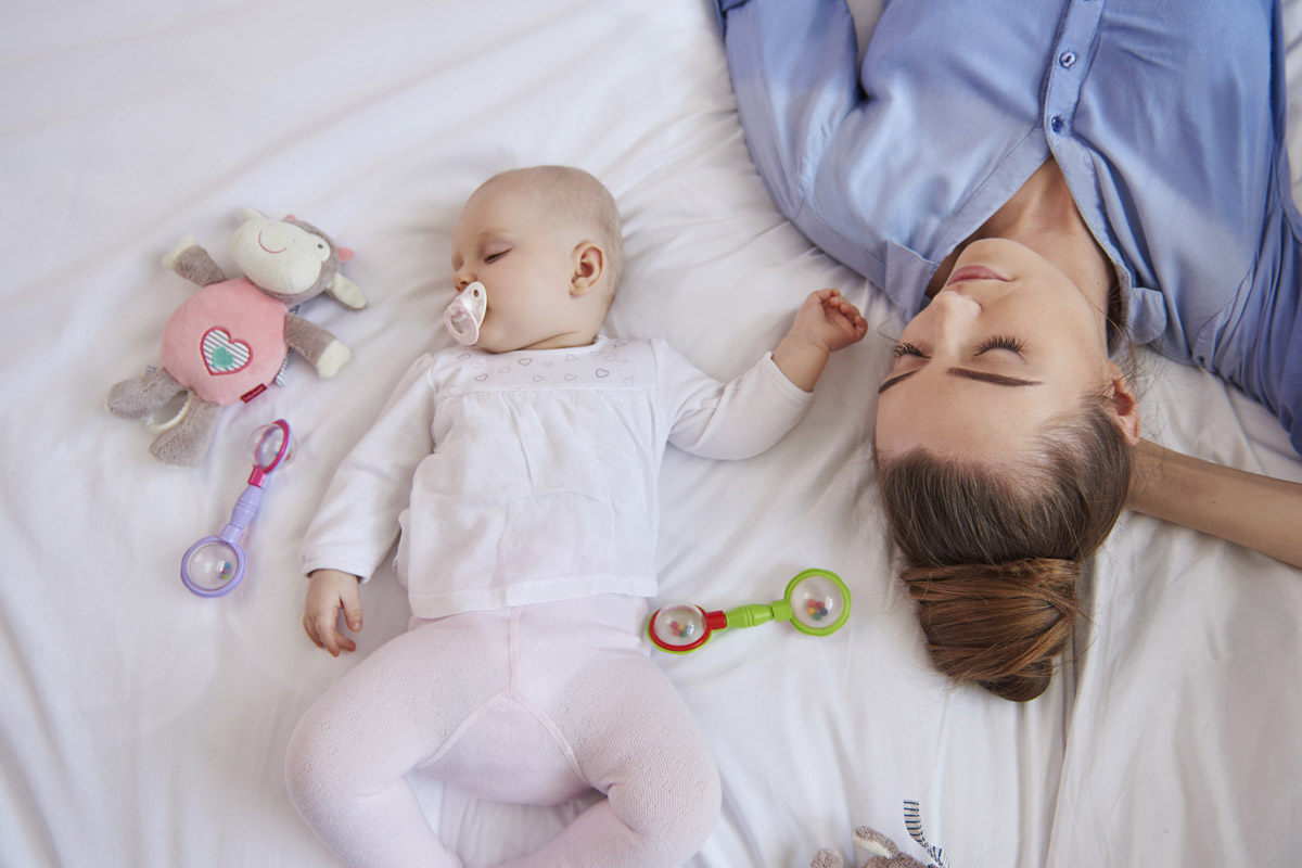 Il rientro a casa con il neonato - mamma e neonato che dormono sereni sdraiati sul letto