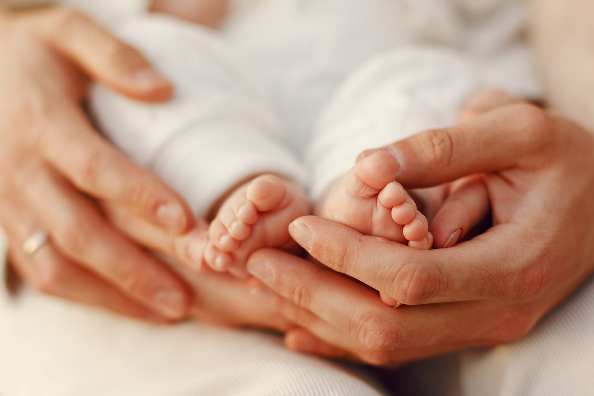 Mani dei genitori che coccolano il neonato - la termoregolazione