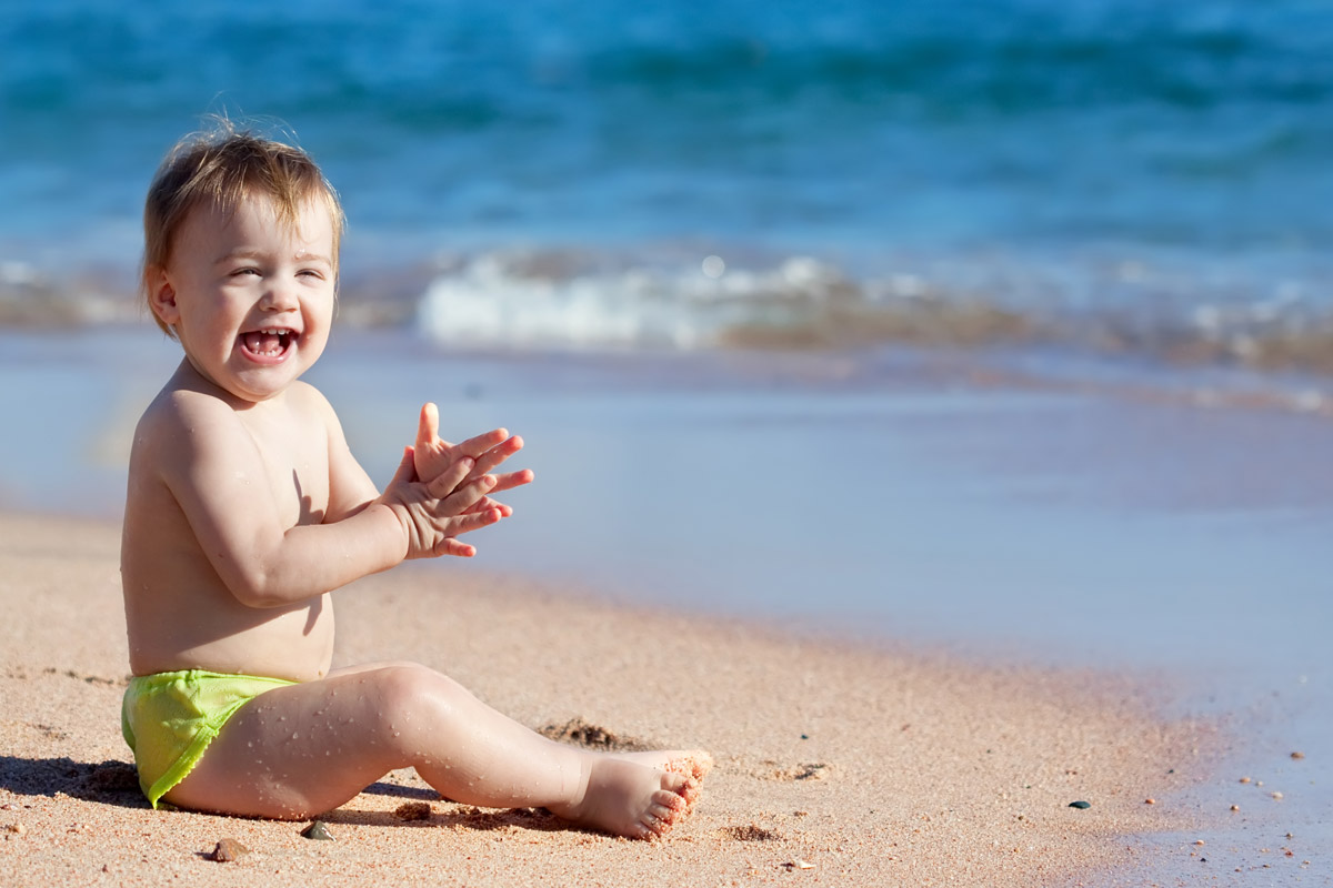 Bambini e estate - Bambino felice seduto in riva al mare